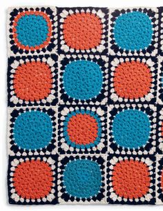 a crocheted square with orange, blue and black circles on the center is shown