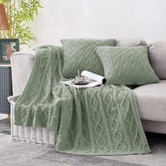 a living room with a couch, chair and table covered in green knitted blankets