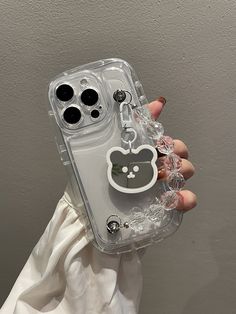 a person holding a clear phone case with a hello kitty keychain attached to it