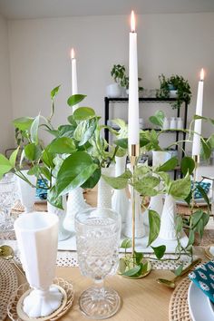 the table is set with candles, plates and vases