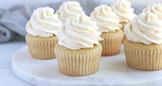 several cupcakes with white frosting sitting on a table next to a blue napkin