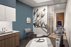 a hospital room with medical equipment in the foreground and an image of flowers on the wall