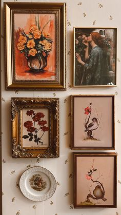 four framed pictures hang on the wall next to a plate and vase with flowers in it