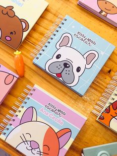 several notebooks with cartoon animals on them sitting on a table next to pens and pencils