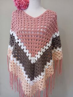 a crocheted shawl with pink flowers on top and brown, white, and tan colors