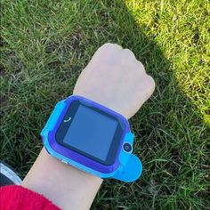 a child's arm with a blue wrist watch on it, in the grass