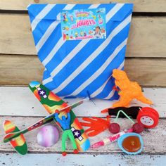 a bag filled with toys sitting on top of a wooden floor next to a blue and white striped bag