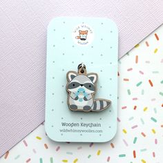 a raccoon brooch sitting on top of a blue card with sprinkles