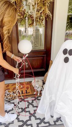 a woman is decorating a halloween tree with white balls and black eyes on it