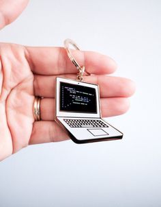 a hand holding a key chain with a laptop on it