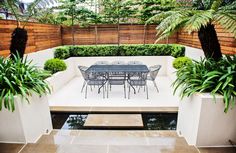 an outdoor dining area with table and chairs, surrounded by potted plants on either side