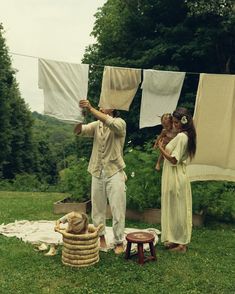 a man and woman standing on top of a lush green field next to laundry lines