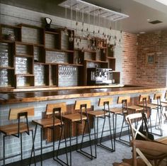 an empty bar with wooden chairs and shelves filled with wine glasses on the back wall