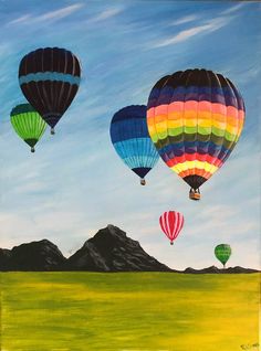 three hot air balloons flying in the sky over a green field with mountains behind them