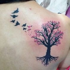 a woman's back with a tree and birds tattoo on her left side shoulder