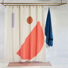 two towels hanging on the wall next to a shower curtain with an orange and blue design