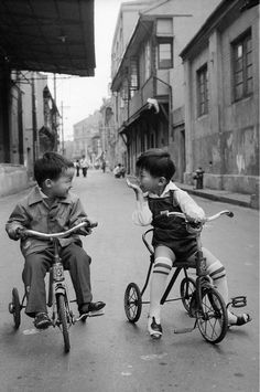 two young boys riding bikes down the street