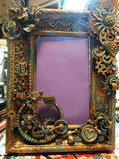 an ornate gold frame sitting on top of a table next to a purple wallpaper