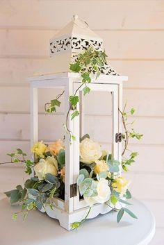 a white lantern with flowers and greenery on it