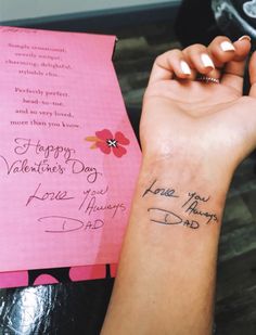 a woman's arm with a small tattoo on it and a pink card that says happy valentine's day