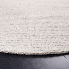 a white rug on top of a wooden floor with a black table in the background