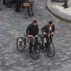 two men are riding bicycles down the street with one man on it's back