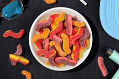 a white bowl filled with gummy bears next to sunglasses