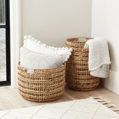 two baskets with pom poms sit on the floor next to an open door