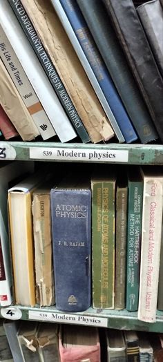 several books are stacked on top of each other in a bookcase with the title, modern physics