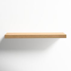 an empty wooden shelf against a white wall