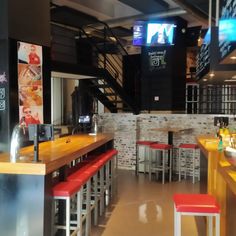 the interior of a fast food restaurant with red and yellow stools in front of it