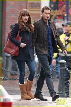 a man and woman walking down the street in winter clothes, one holding a red handbag