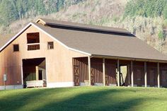 a large barn sitting on top of a lush green hillside