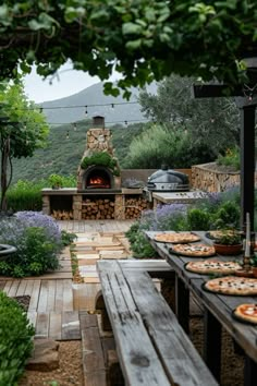 an outdoor pizza oven surrounded by wooden benches and tables with food on them in the foreground