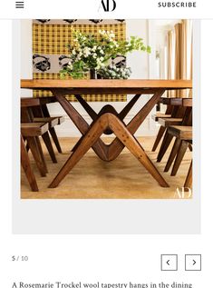 a wooden table with chairs and flowers on it in the middle of a living room