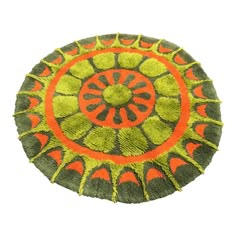 an orange and green circular rug on a white background