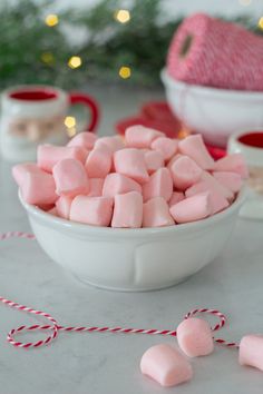 pink marshmallows in a white bowl on a table next to christmas decorations