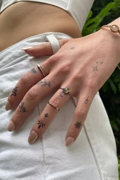 a woman's hand with tattoos on her left wrist and two fingers in the other