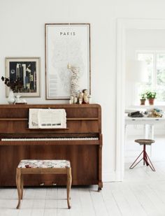 a living room with a piano in the center and pictures on the wall above it