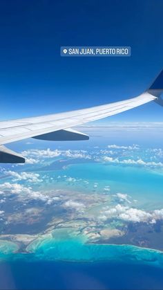 an airplane wing flying over the ocean and land