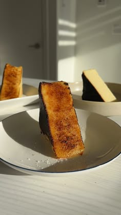 three pieces of cake on a white plate next to another piece of cheese and bread