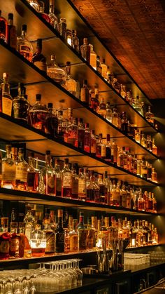 many bottles and glasses are lined up on the shelves