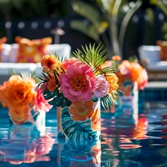 colorful flowers in vases sitting on the edge of a pool at a wedding reception