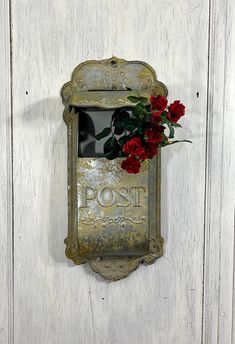 a red rose is placed in an old post box on the side of a white door