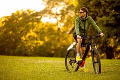 a man riding on the back of a bike down a lush green field