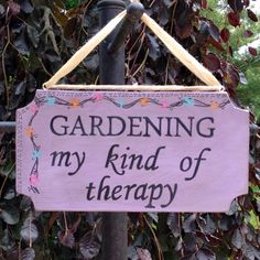 a sign that says gardening is my kind of therapy hanging on a pole in front of some leaves