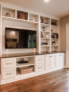 a large entertainment center with white cabinets and wood flooring in a living room area