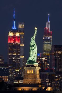 the statue of liberty is lit up in red, white and blue for the new york city skyline