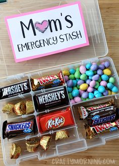 a plastic container filled with candy and candies on top of a wooden table next to a sign that says mom's emergency stash