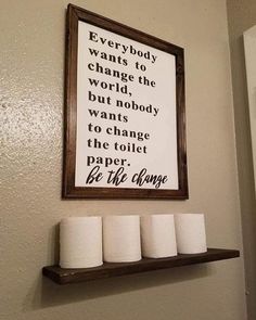 a bathroom with toilet paper rolls on the shelf and a sign above it that says, every body wants to change the world but nobody wants to change